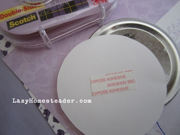 Double sided tape adhere the paper circle to the lid.